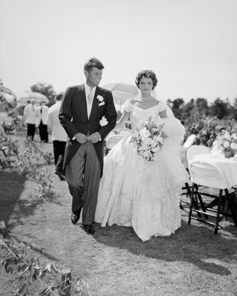 John F. Kennedy walks alongside his bride Jacqueline at their outdoor wedding reception in Newport, Rhode Island in 1953.