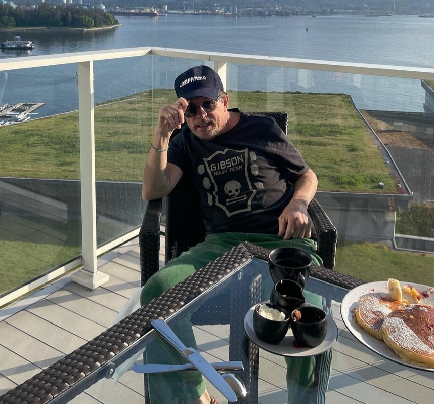 Michael J Fox sitting in a chair on a balcony. 