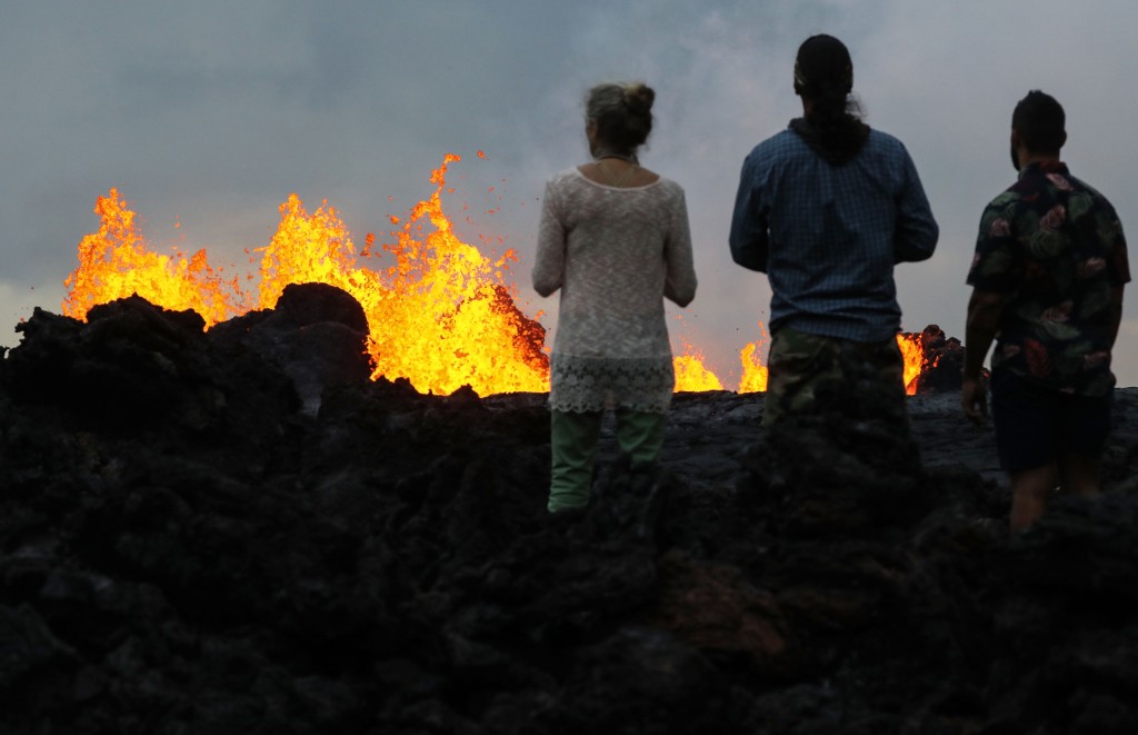 Onlookers watch as lava from a Kilauea volcano fissure erupts in 2018.