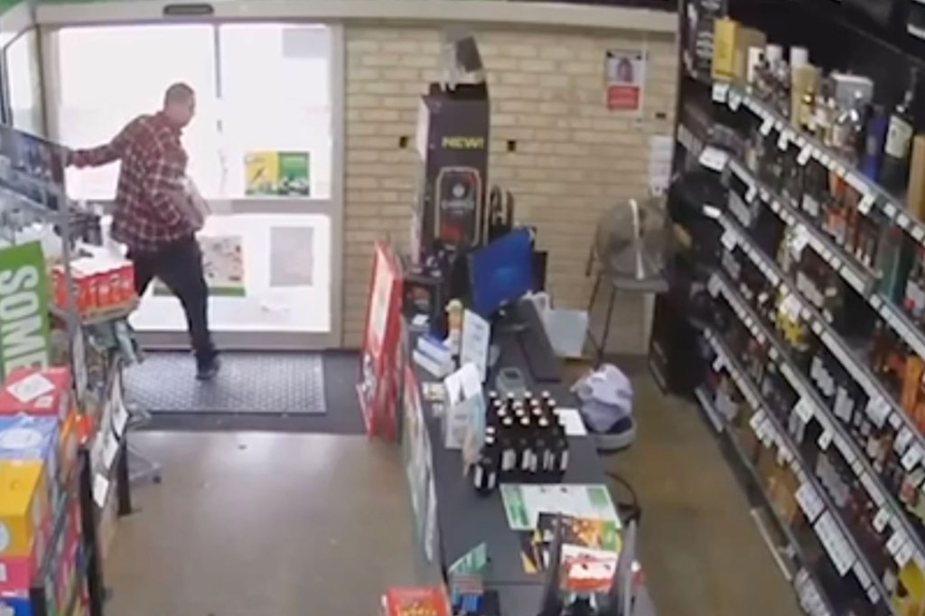 Man in red flannel tries to open automatic door with hands.