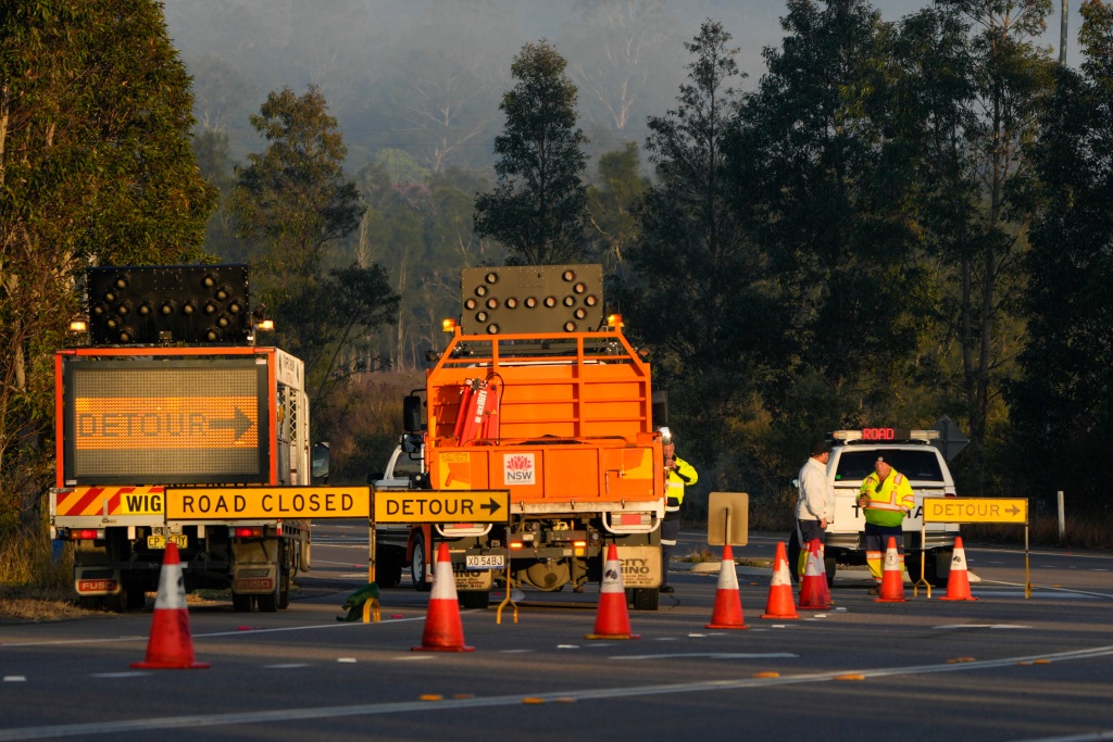 Orange signs and traffic cones mark a road closure and point in the direction a detour. 