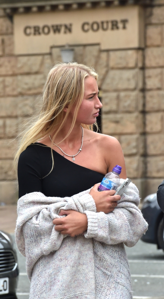 Georgia Bilham leaves Crown Court in a black asymmetrical top with a sweater around her arms.