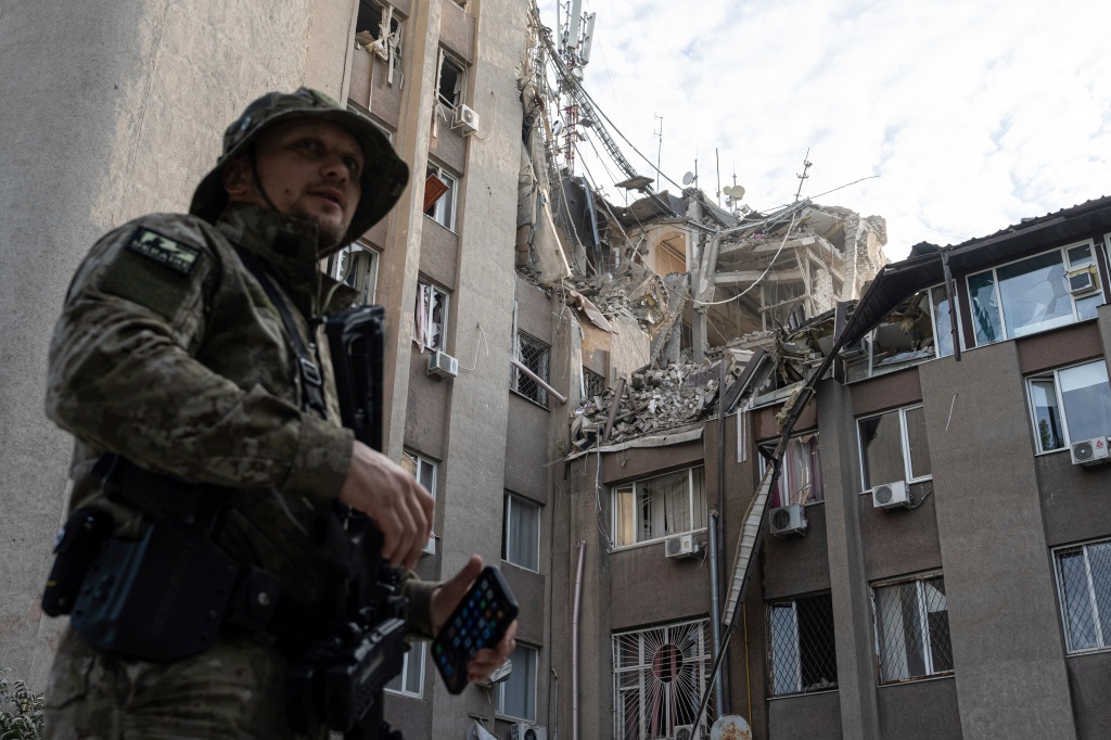 A Ukrainian serviceman stands in front of a building which was heavily damaged by a Russian airstrike in Kherson, Ukraine. 