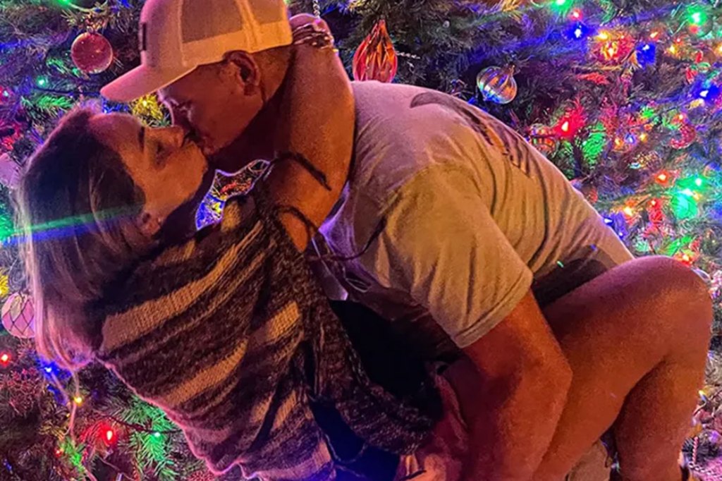 Brittany Holbrook and Tyler Nulisch kiss in front of a Christmas tree in a past photo. 