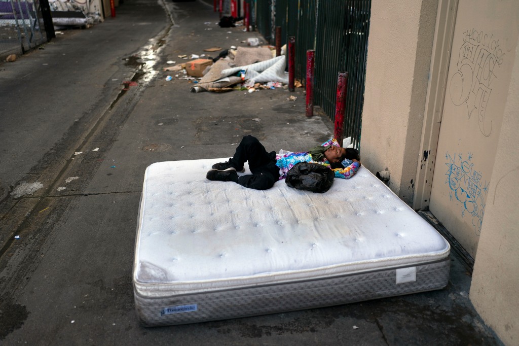 A homeless man sleeps on a discarded mattress in Los Angeles, July 21, 2022.