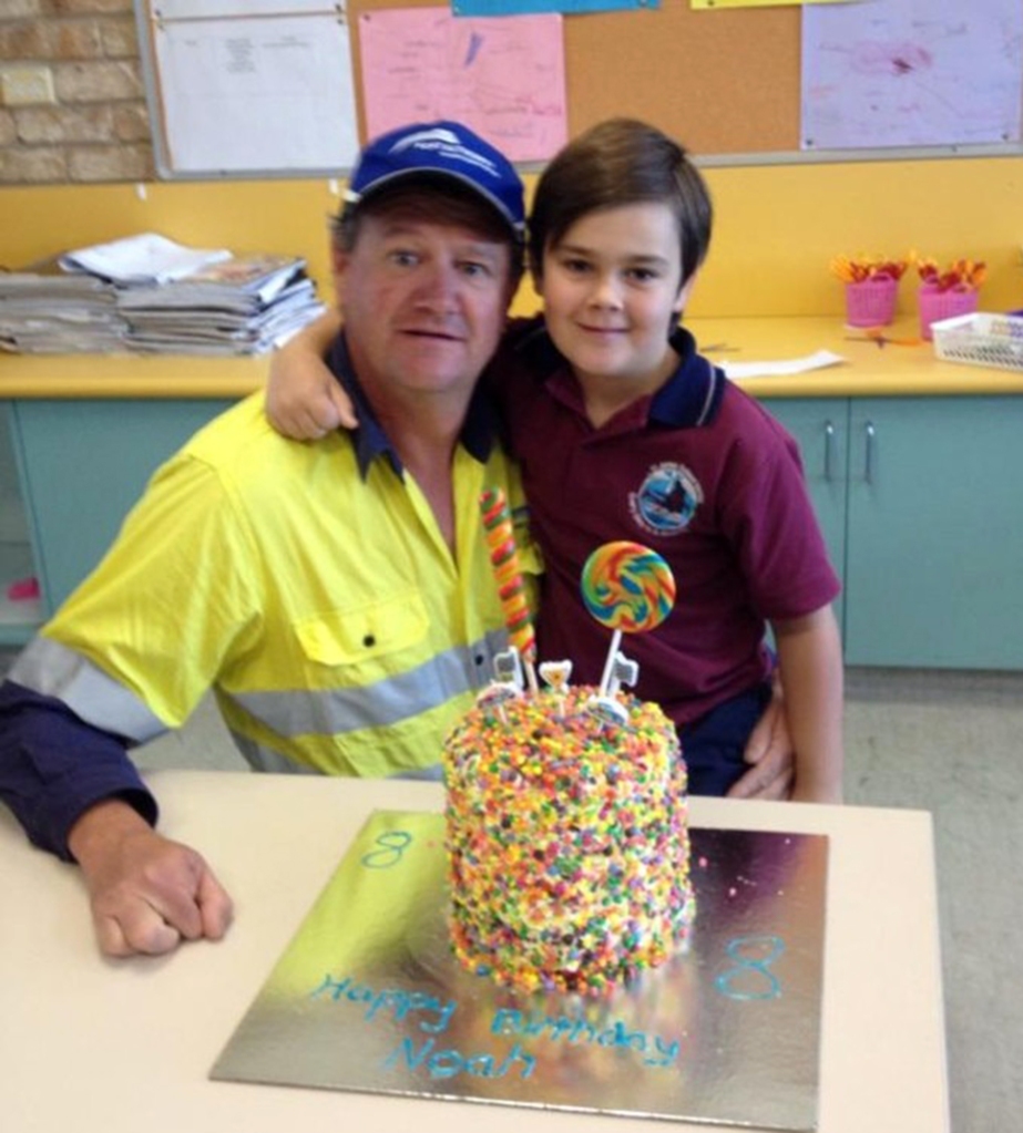 Wayne and Noah pose in front of a birthday cake