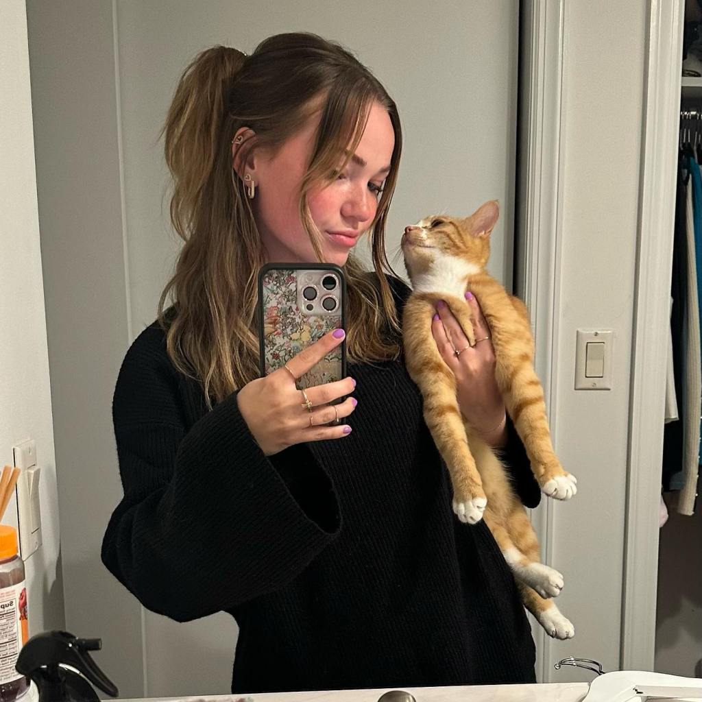 Alyssa McKay holding her cat Indiana and taking a mirror selfie with her phone