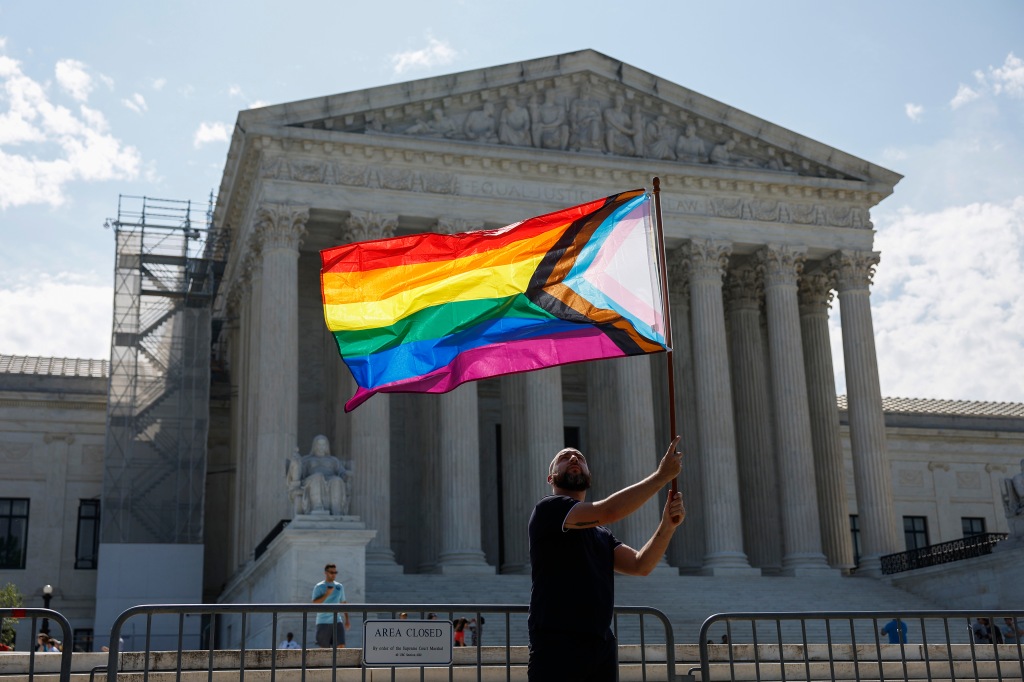 US Supreme Court with an LGBTQ flag in front.