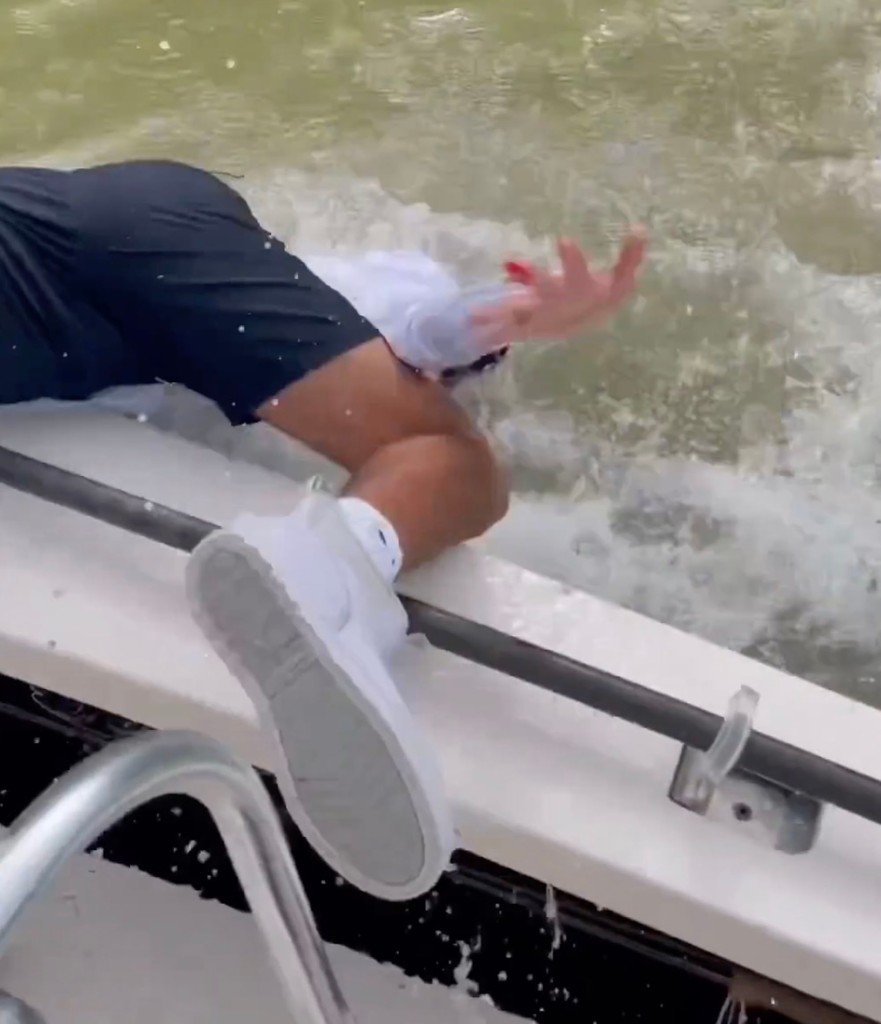 Man falls overboard headfirst into water with a bleeding hand. 