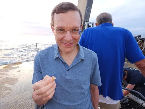 Avi Loeb holding a magnetic piece of debris painted in white, with a composition of a human-made TiO2 paint.