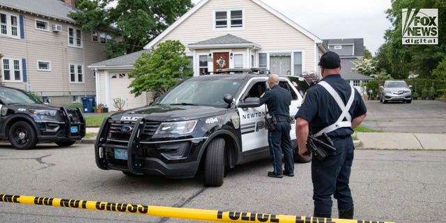 Police officers gather outside of the home where a triple homicide occurred in Newton, Massachusetts