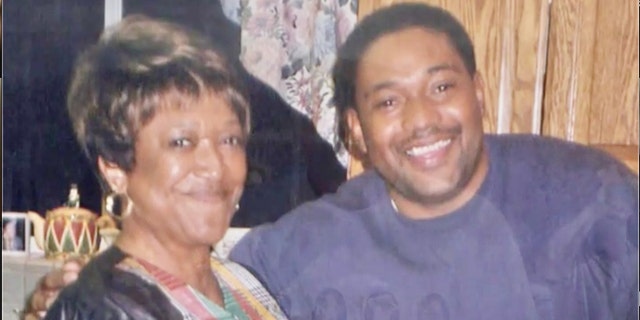 Minnie Smith smiling next to her son wearing a purple sweater