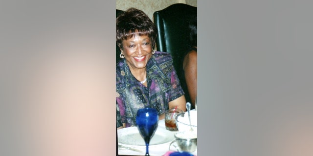 Minnie Smith wearing a multicolored blouse smiling at a dinner table