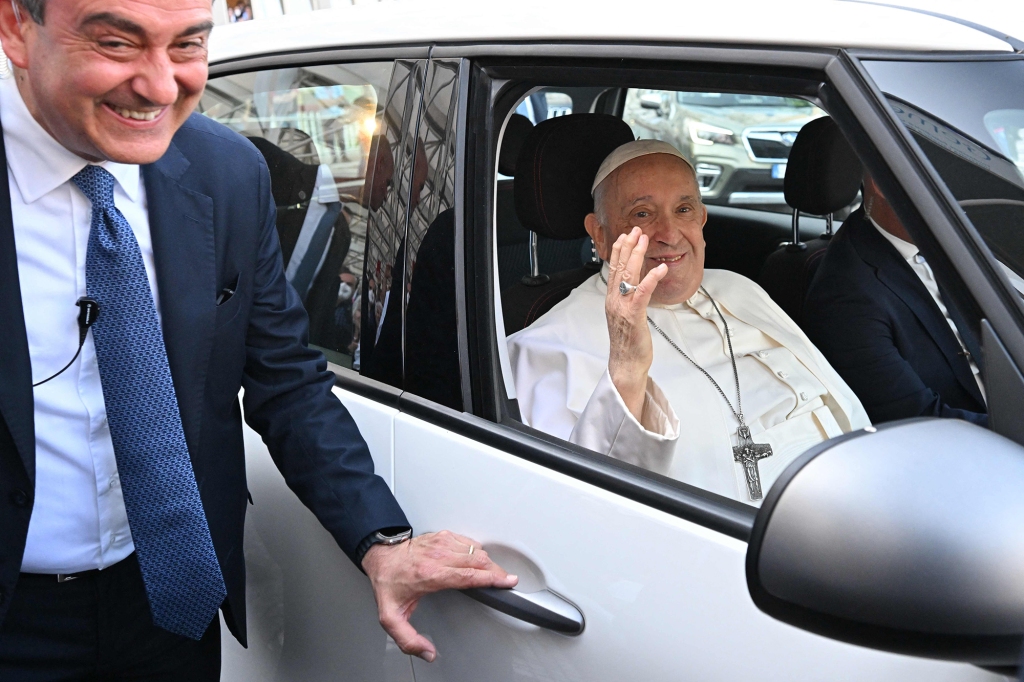 Pope Francis, escorted by  Vatican Security Chief, Gianluca Gauzzi Broccoletti (L), waves as he leaves after being discharged from the Gemelli hospital in Rome on June 16, 2023,