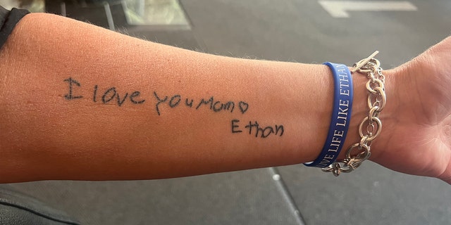 A forearm tattoo reading "I love you mom."