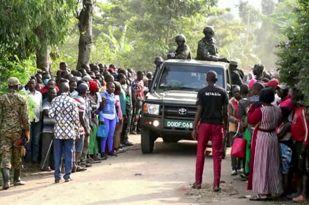 security forces drive past a crowd of people gathered outside the Lhubiriha Secondary School following an attack on the school near the border with Congo, in Mpondwe, Uganda, Saturday, June 17, 2023. 