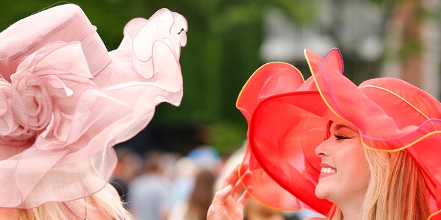 Two spectators wearing extravagant, colorful hats for the Belmont Stakes