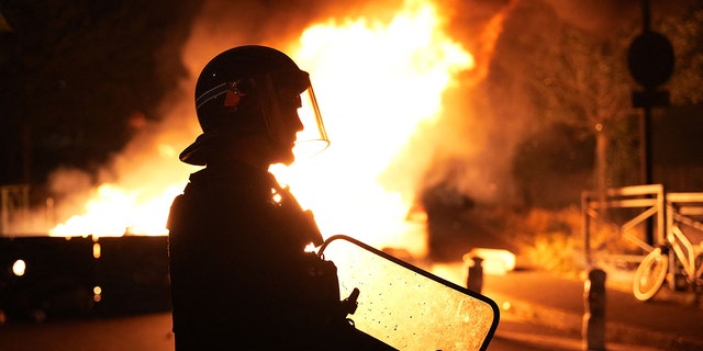 A firefighter looks on as vehicles burn following riots in Nanterre, west of Paris