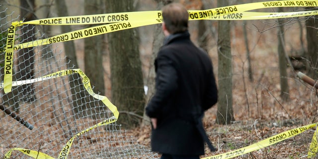 A man walks past police tape near a crime scene in Central Islip, N.Y., Thursday, April 13, 2017. Police say the bodies of four apparent homicide victims have been found in a Long Island park. The victims were found in a wooded area near a recreation center in Central Islip. (AP Photo/Seth Wenig)