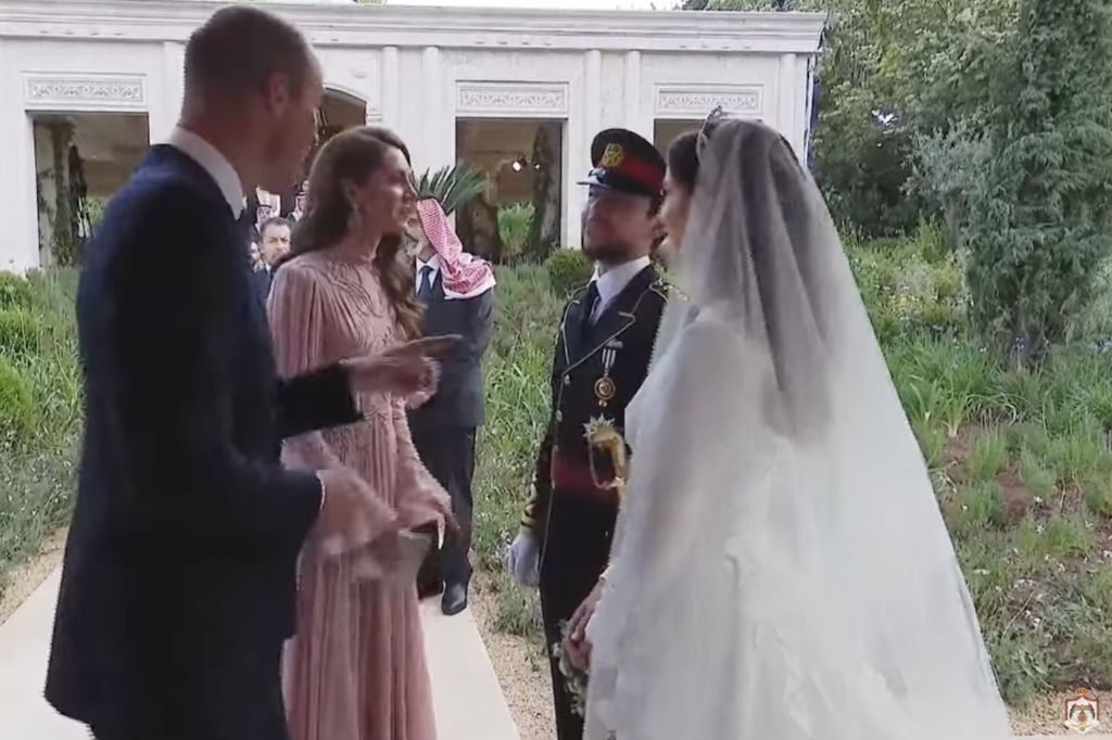 Prince William gestures to Crown Prince Al Hussein to wrap up his conversation with Princess Kate.