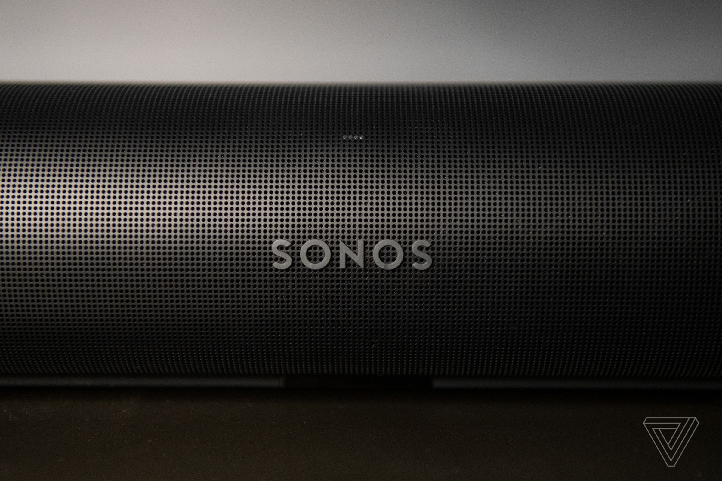 A detail shot of the front of the Sonos Arc, showing the Sonos logo and many perforated holes in the outer casing.