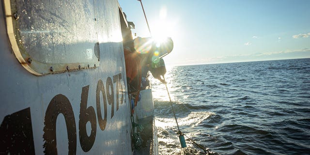 fisherman reeling in buoy onto boat