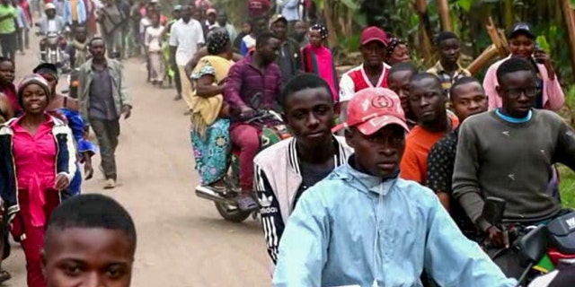 People make their way towards the Lhubiriha Secondary School following an attack on the school near the Congo border