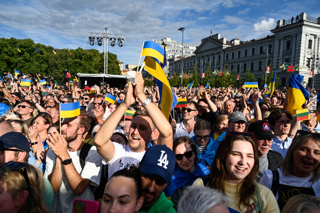 People hold Ukrainian flags and shout slogans as the President of Ukraine, Volodymyr Zelenskyy delivers a speech during the Raising the Flag for Ukraine NATO event  on July 11, 2023 in Vilnius, Lithuania.