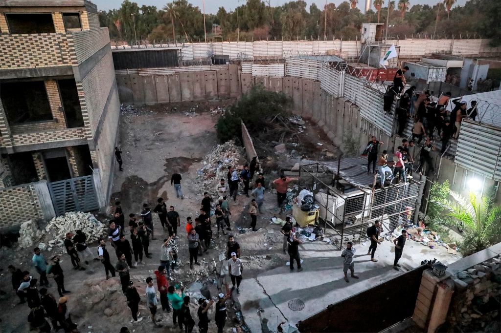 Protesters climb the fence outside the Swedish embassy on Thursday, July 20 in Baghdad, Iraq.