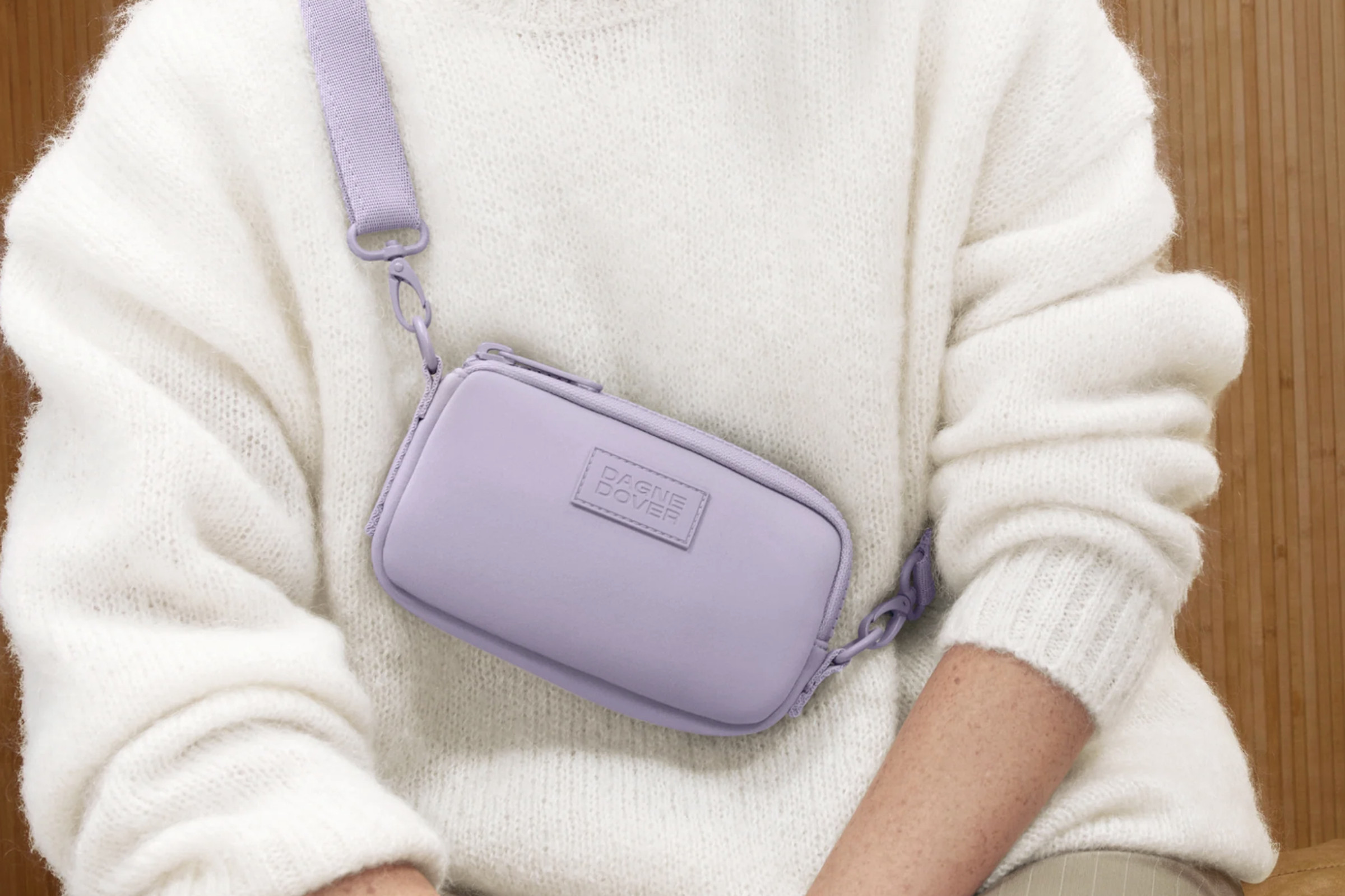 Person in white sweater where lavender sling bag.