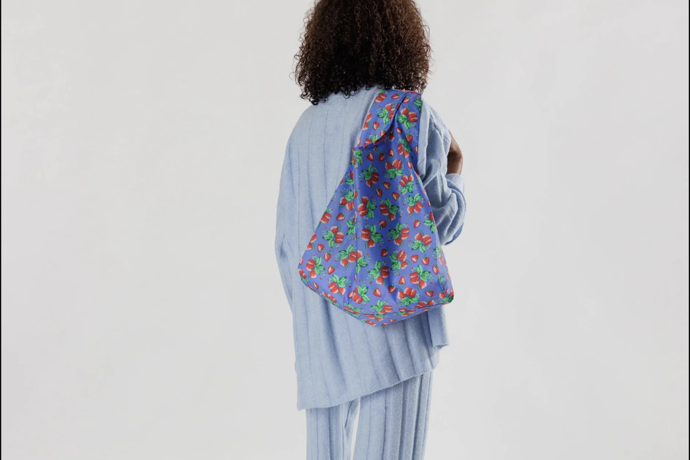 Woman carrying flowered bag over one shoulder.