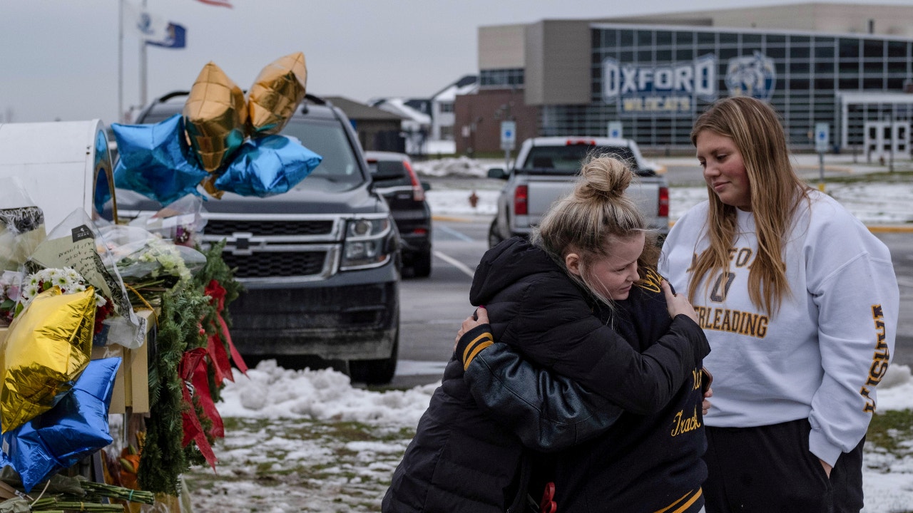 People embrace as they pay their respects at a memorial at Oxford High School, a day after a shooting that left four dead and eight injured, in Oxford, Michigan. Oxford Community Schools announced Monday that all classes would be canceled Tuesday after a threat to a middle school.