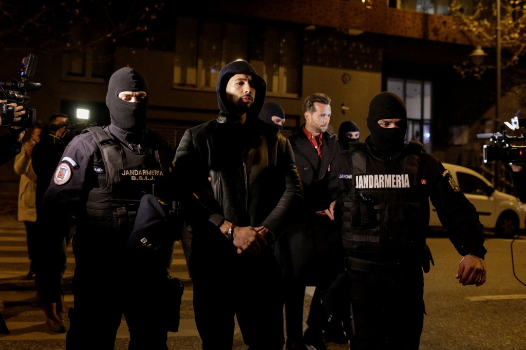 Andrew Tate and Tristan Tate are escorted by police officers outside the headquarters of the Directorate for Investigating Organized Crime and Terrorism in Bucharest (DIICOT) after being detained for 24 hours, in Bucharest, Romania, December 29, 2022.