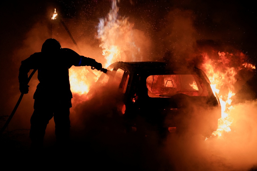 French firefighter putting out a burning car.