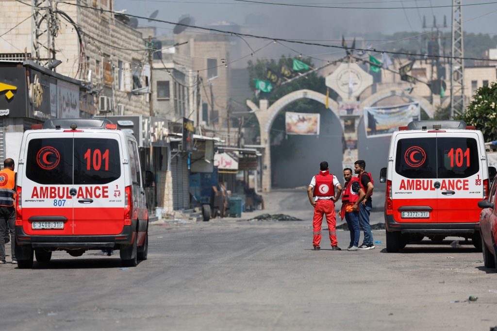 Palestinian medics stand by as smoke rises during an Israeli military operation in Jenin, in the Israeli-occupied West Bank on July 3, 2023. 