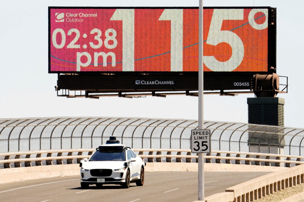 A car drives on Seventh Street as the temperature of 115 degrees is displayed on a digital billboard in downtown Phoenix, Arizona. 