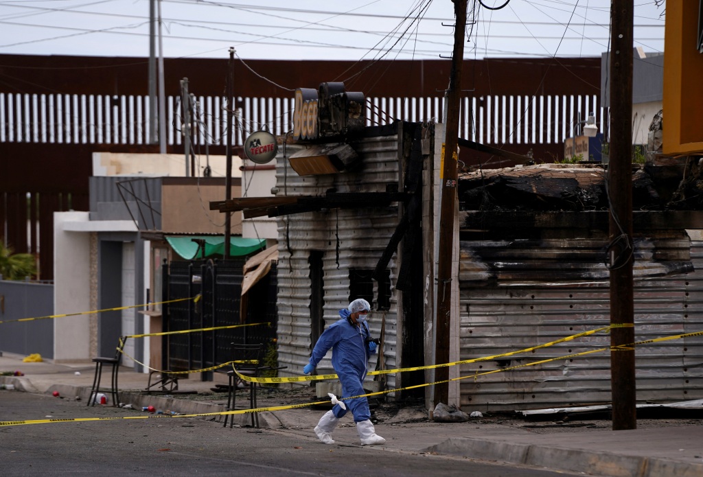 A forensic technician works at a scene where a man threw a Molotov cocktail bomb after being kicked out of a bar for bad behavior, leaving several victims, according to Sonora state authorities, in San Luis Rio Colorado, Mexico July 22, 2023. 