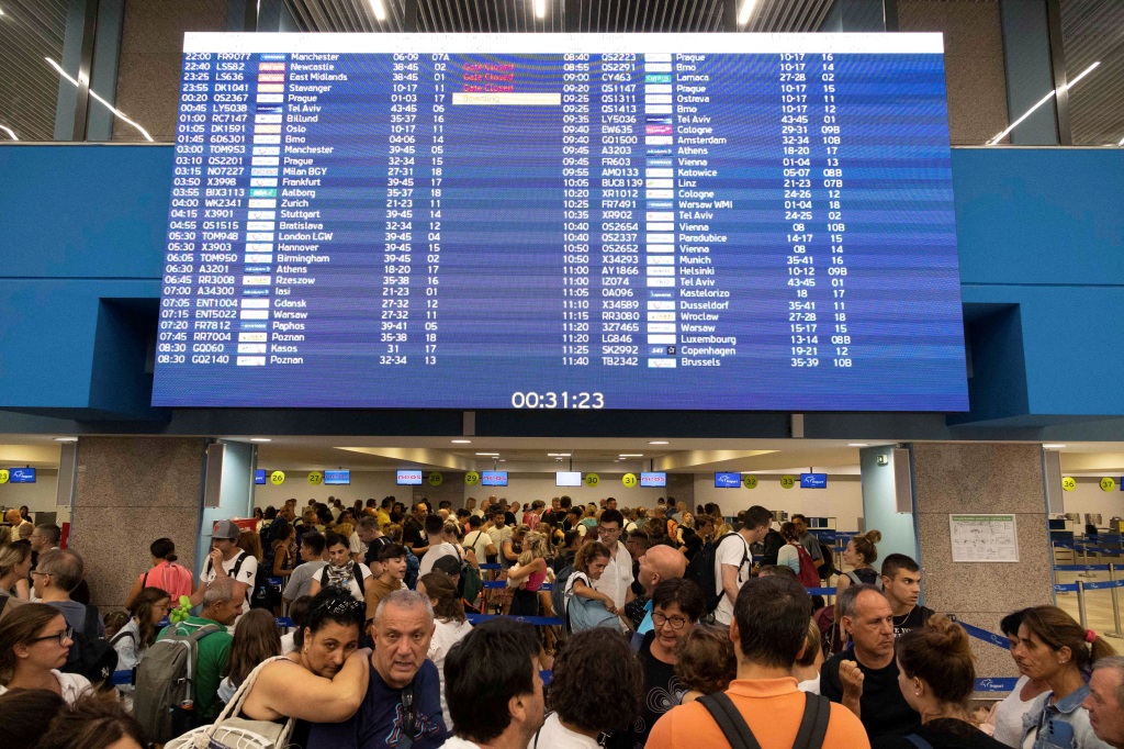 Tourists line up at check-in counters as they wait for departing planes at the airport after being evacuated near Rhodes, Greece, on July 24, 2023. 