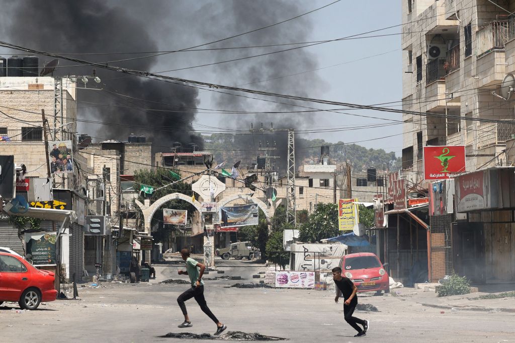 Palestinian youths run for cover amid clashes during an Israeli military operation in Jenin city in the occupied West Bank, on July 3, 2023.