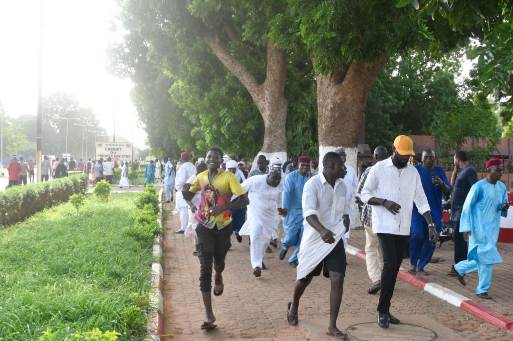 Demonstrators flee after warning shots were fired while they protest Bazoum's detention.
