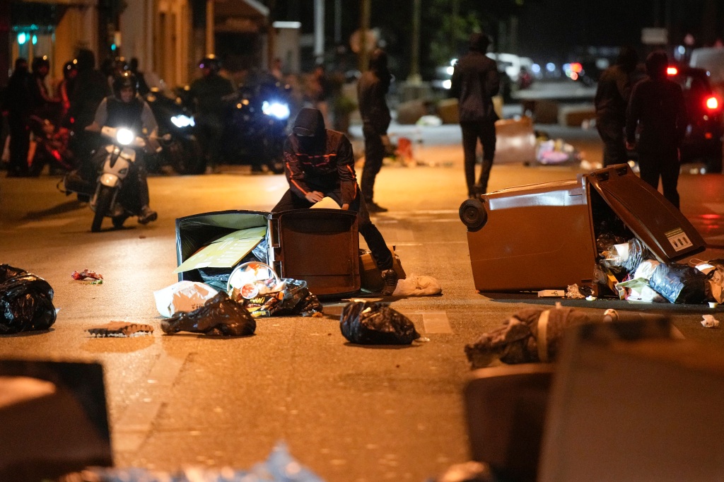 Protesters block a street with garbage cans in Colombes, outside Paris, France, Saturday, July 1, 2023.