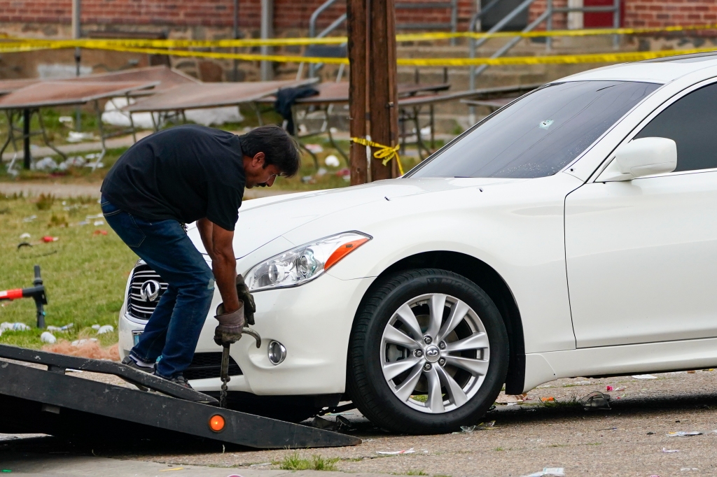 A tow truck operator removes a vehicle with multiple bullet holes near the area of a mass shooting incident 
