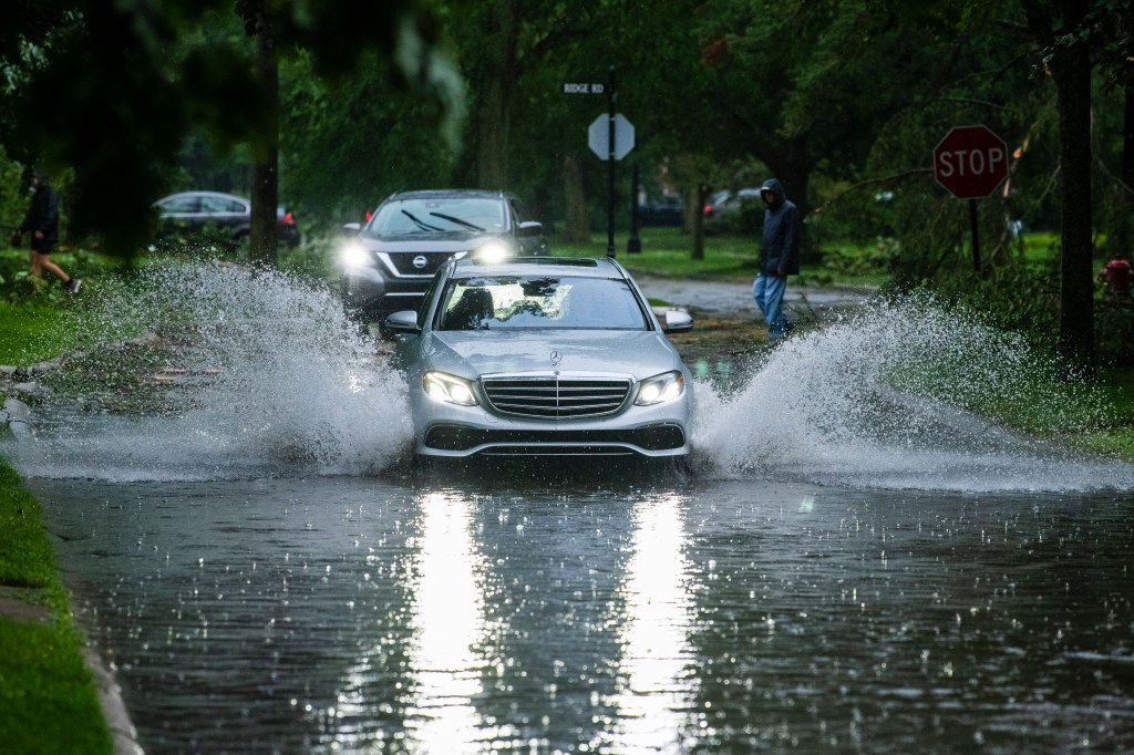 Vehicles navigate a flooded road in Grosse Pointe Farms, Mich., after the storm slammed the area on July 26, 2023. 