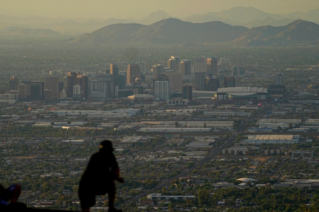 A man overlooks downtown Phoenix at sunset atop South Mountain on July 30, 2023. 