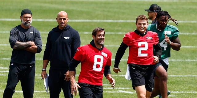 Aaron Rodgers and Zach Wilson warm up before a training session