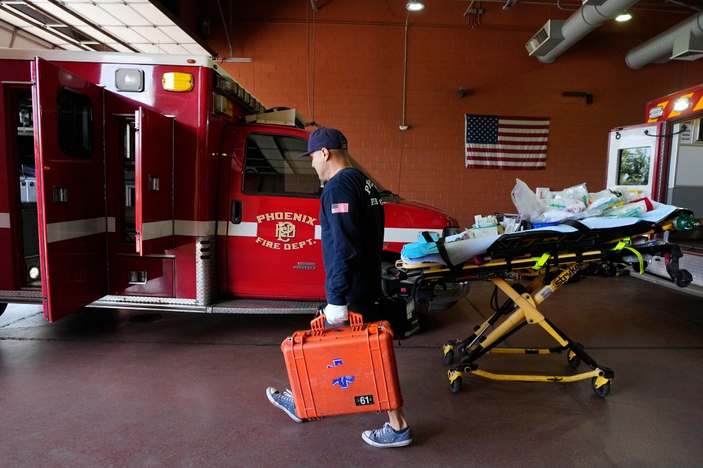 A Phoenix Fire Department firefighter walks with gear inside the station, as scorching weather plagues the area. 
