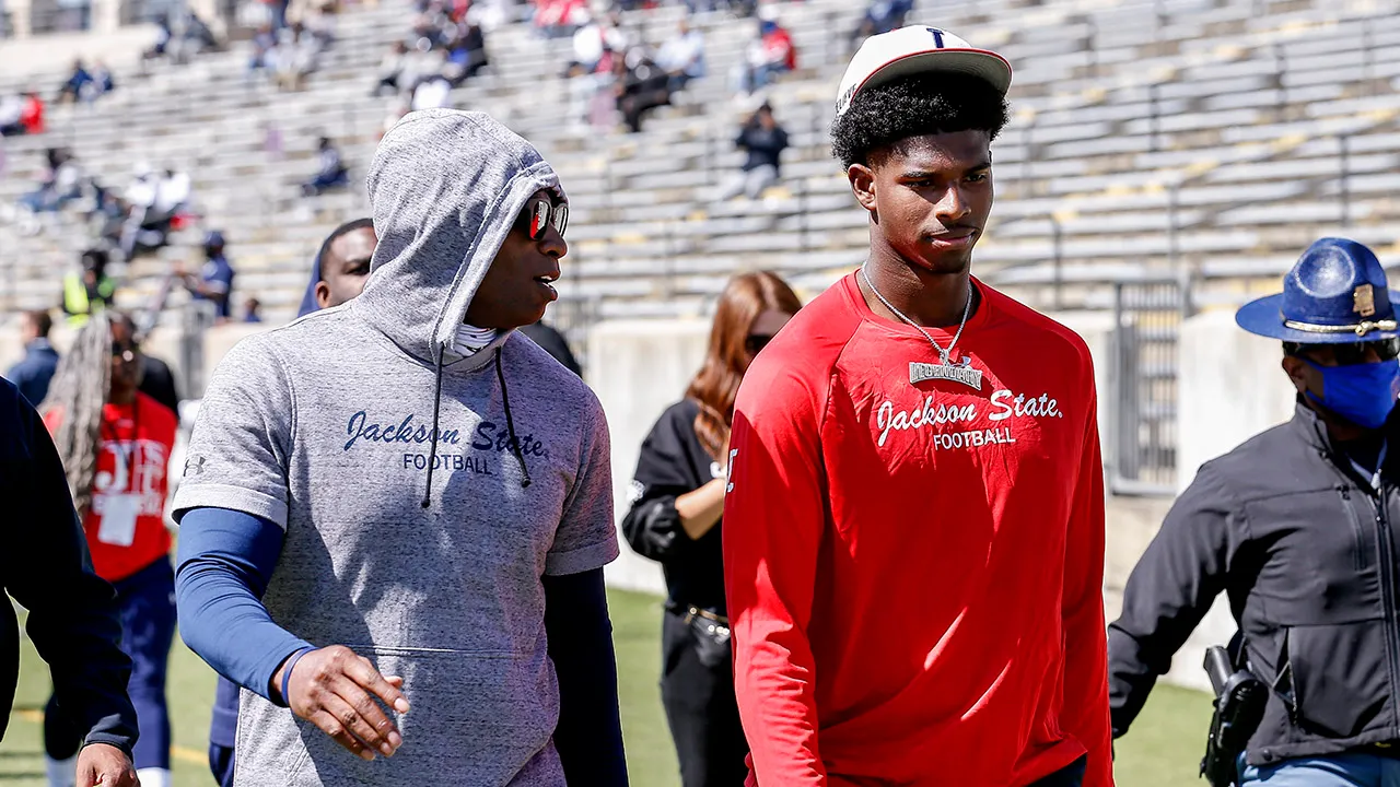 Deion Sanders walks to the locker room with his son and quarterback Shedeur