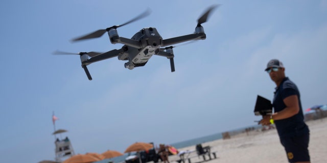 A lifeguard operates a drone