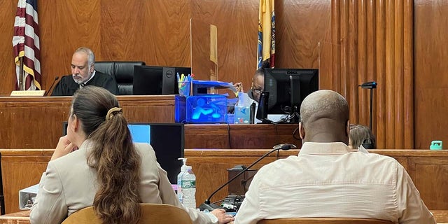 Judge Gary Wilcox in background in wide courtroom shot