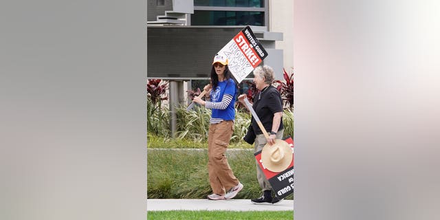 Sarah Silverman at a Writers Gild strike carrying a sign.